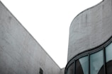 A modern architectural structure with a focus on geometric lines and smooth curves. The building exterior features large, textured stone tiles and expansive glass windows, conveying a sense of minimalistic elegance.