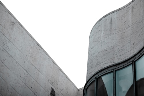 A modern architectural structure with a focus on geometric lines and smooth curves. The building exterior features large, textured stone tiles and expansive glass windows, conveying a sense of minimalistic elegance.