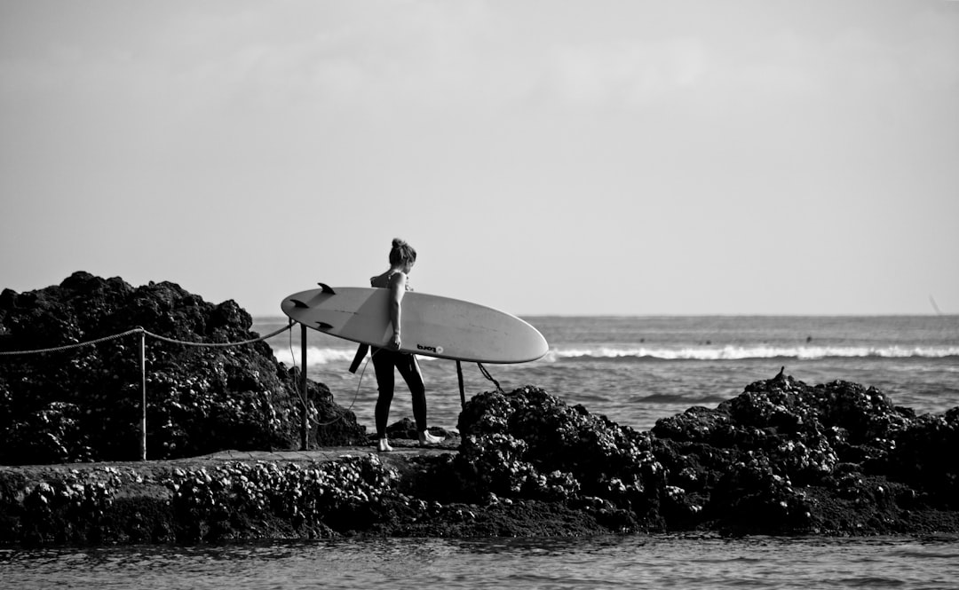 grayscale photography of woman holding surfing board