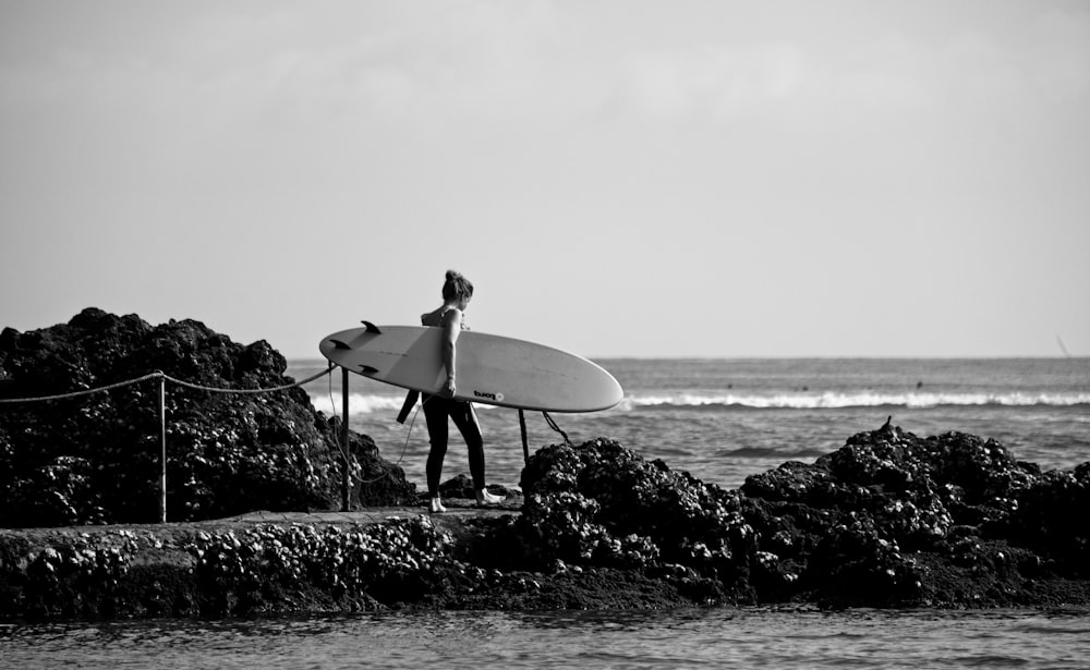 grayscale photography of woman holding surfing board