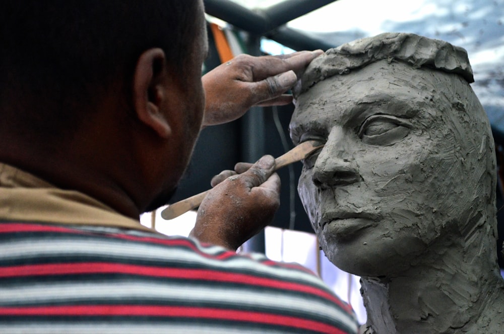 man sculpting man's eye