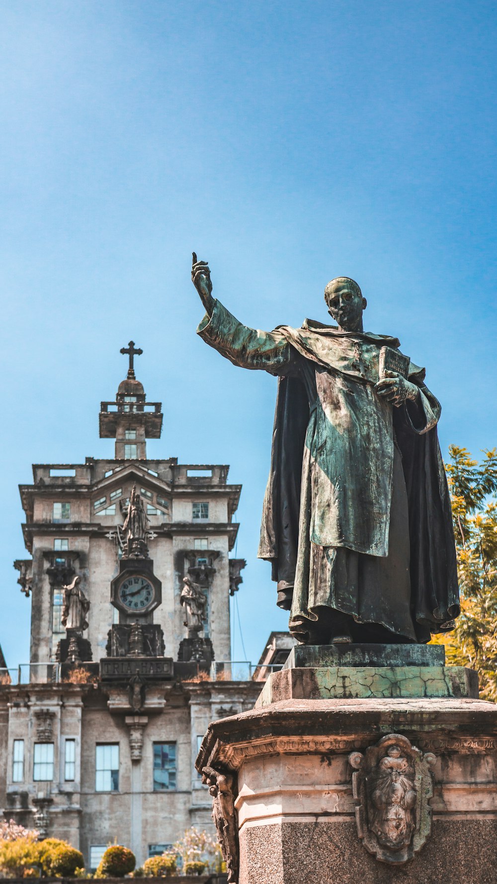 man holding book statue near building