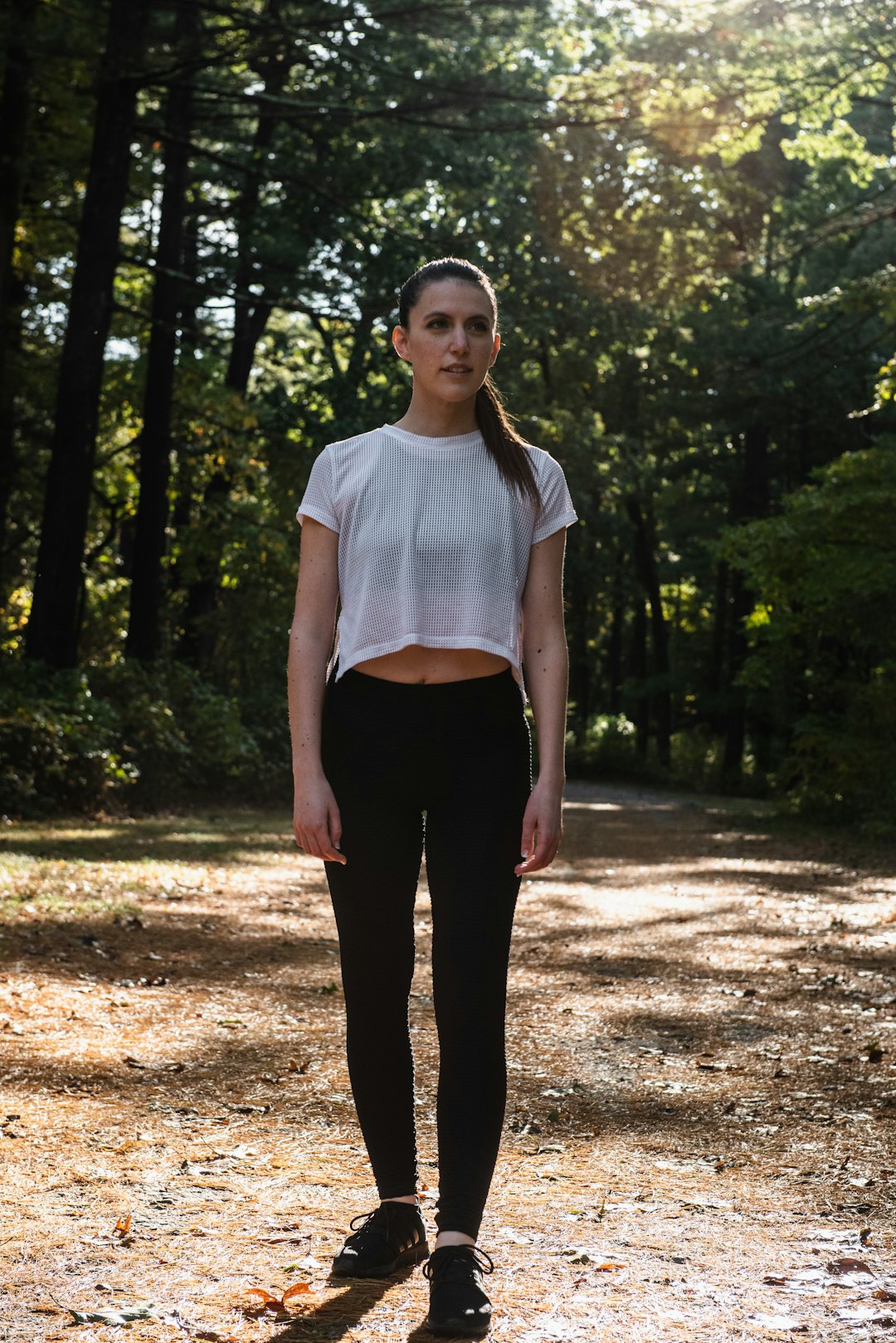 woman in white crop t-shirt standing in forest