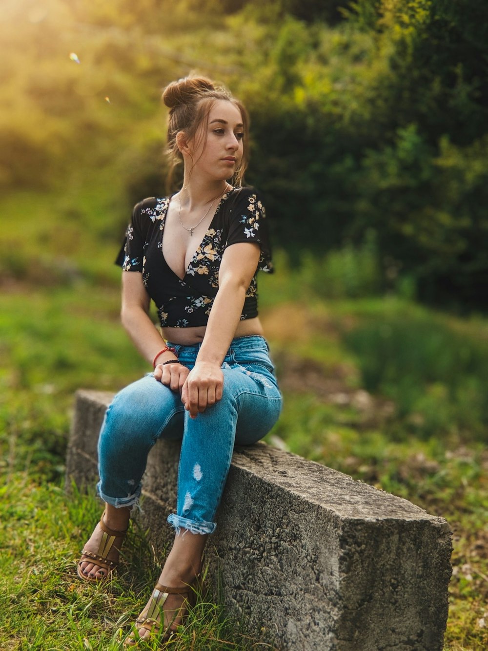 woman in blue den]im jeans sitting on concrete surface