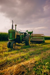 A rugged mobile repair truck parked beside a large tractor under a cloudy sky at dusk.