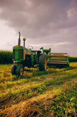 A rugged mobile repair truck parked beside a large tractor under a cloudy sky at dusk.