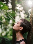 boy leaning back on tree