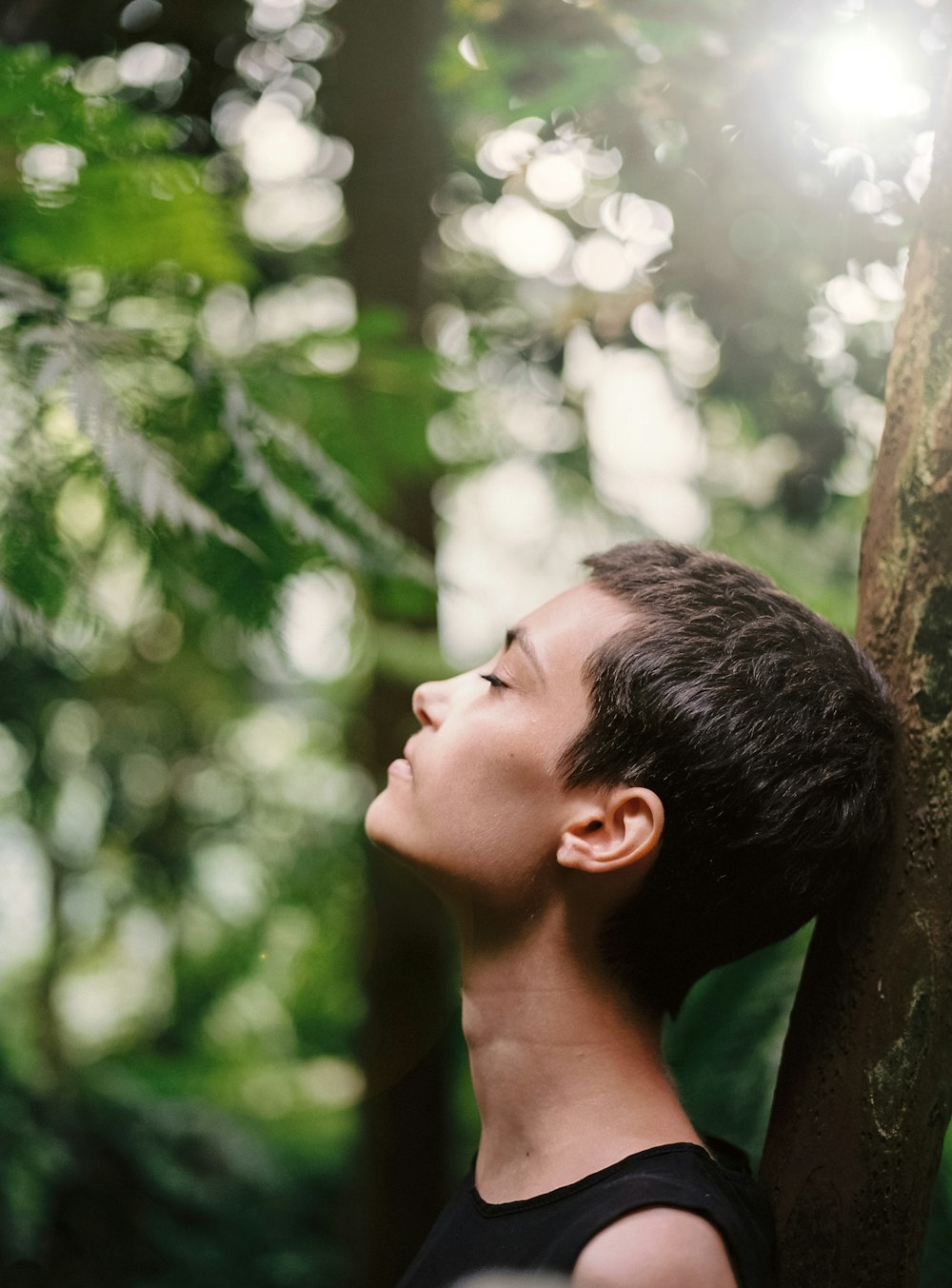 boy leaning back on tree