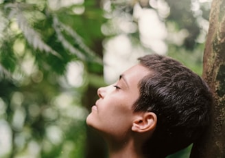 boy leaning back on tree