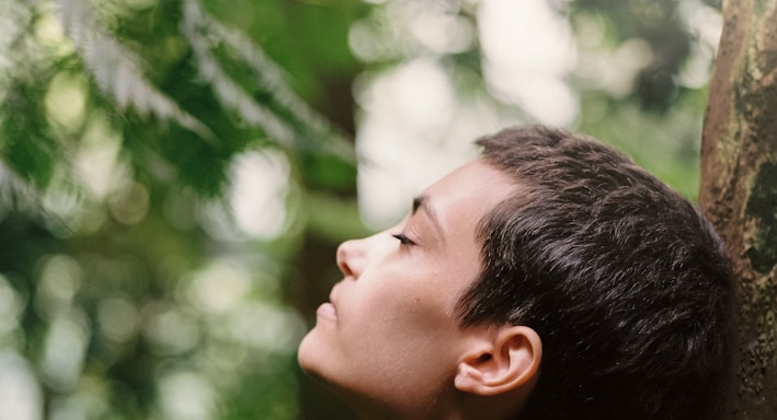 boy leaning back on tree