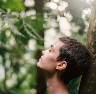 boy leaning back on tree