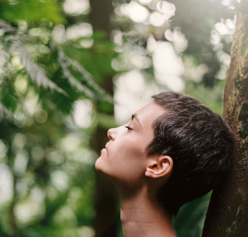 boy leaning back on tree