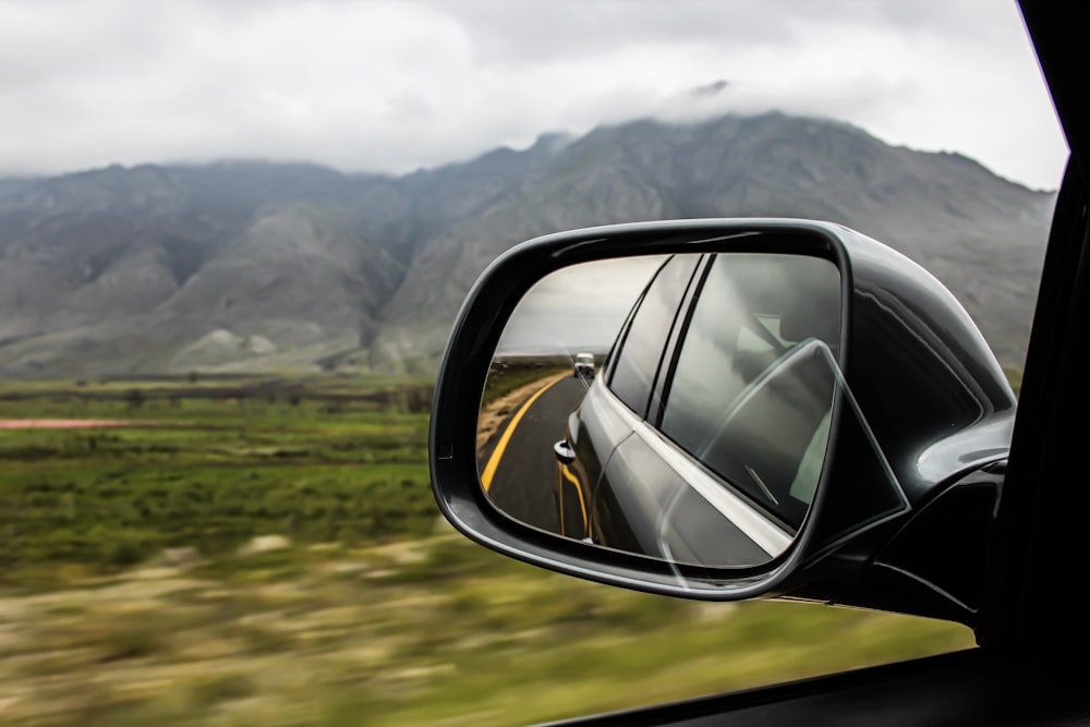 view of vehicle side mirror with vehicle at the back