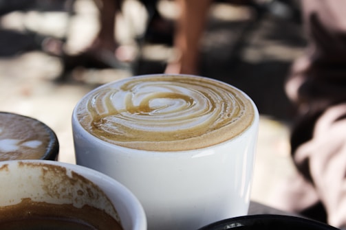 Close-up of a steaming cup of Karis Mushroom Coffee with visible swirls of creamy coconut milk.