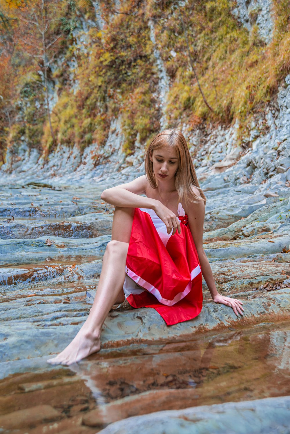 woman in white and red dress sitting on rocks