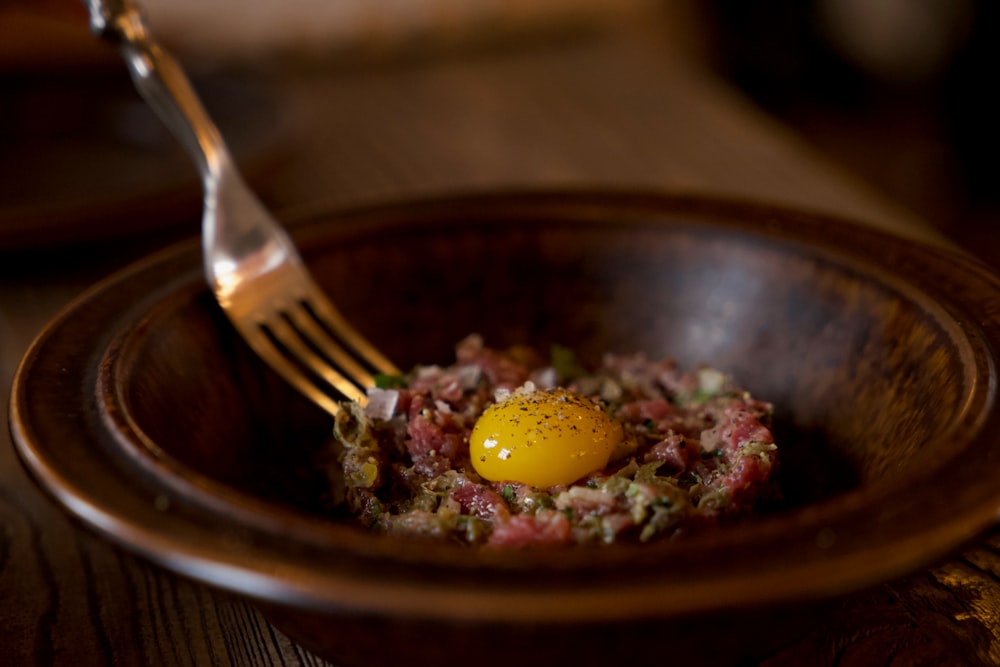 egg-topped meat dish in round brown bowl