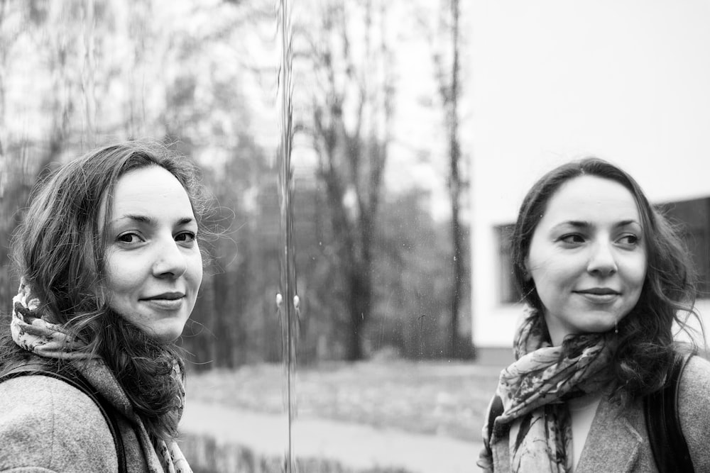 Photographie en niveaux de gris d’une femme debout et souriante