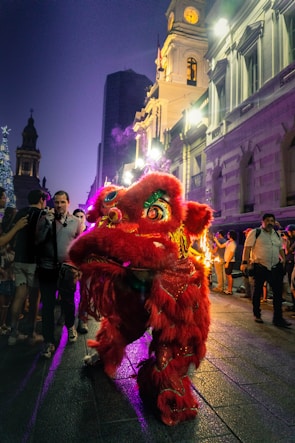 Leo the lion joyfully playing a drum under bright circus lights.