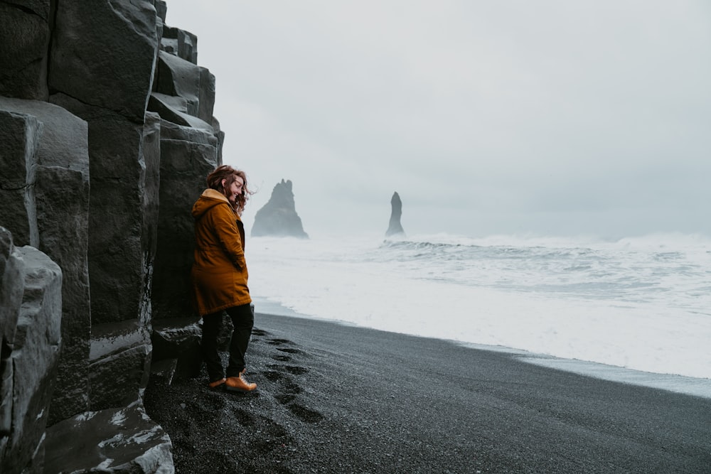 woman wears brown jacket standing near the ocean