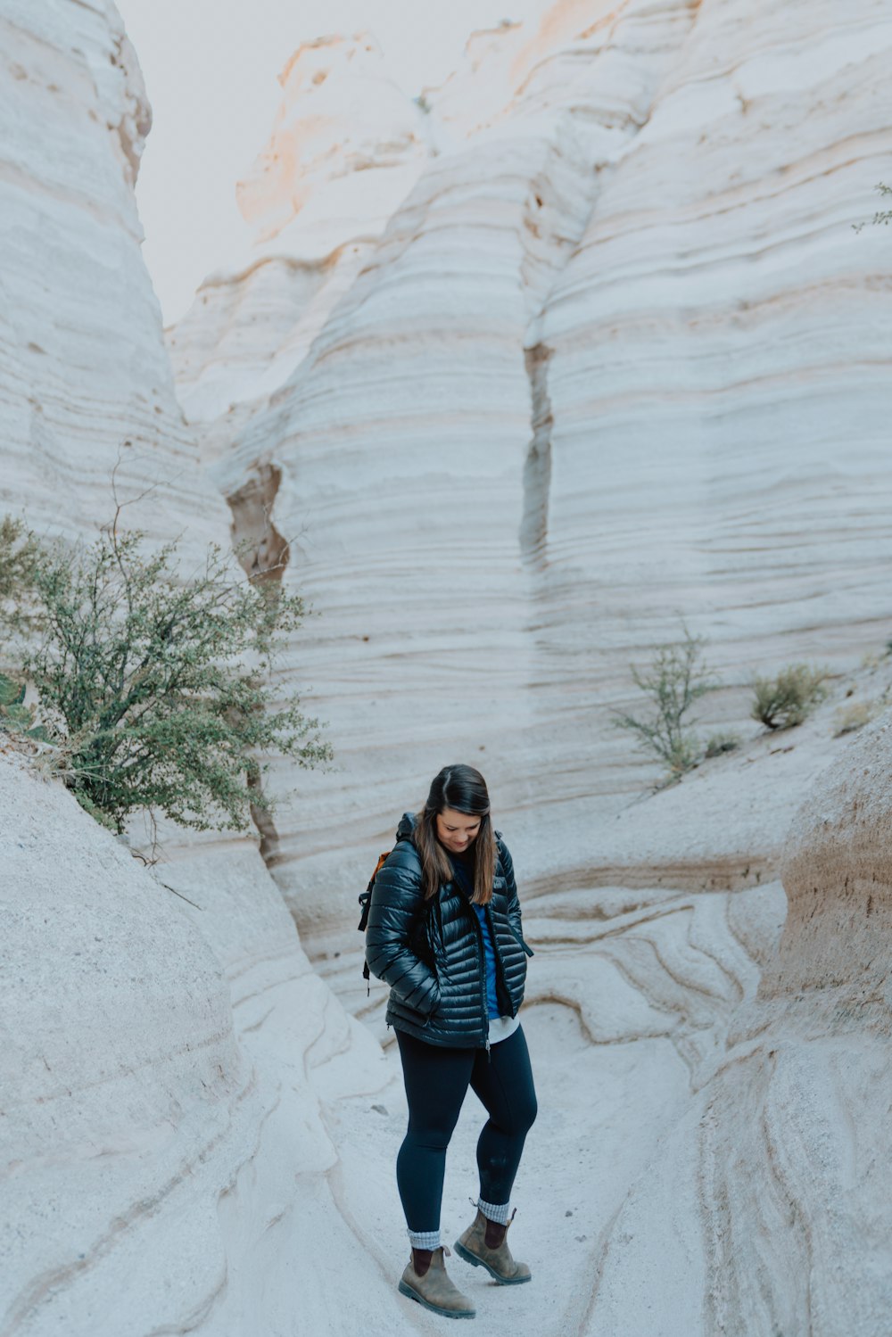 woman in blue jacket standing on white stone cave