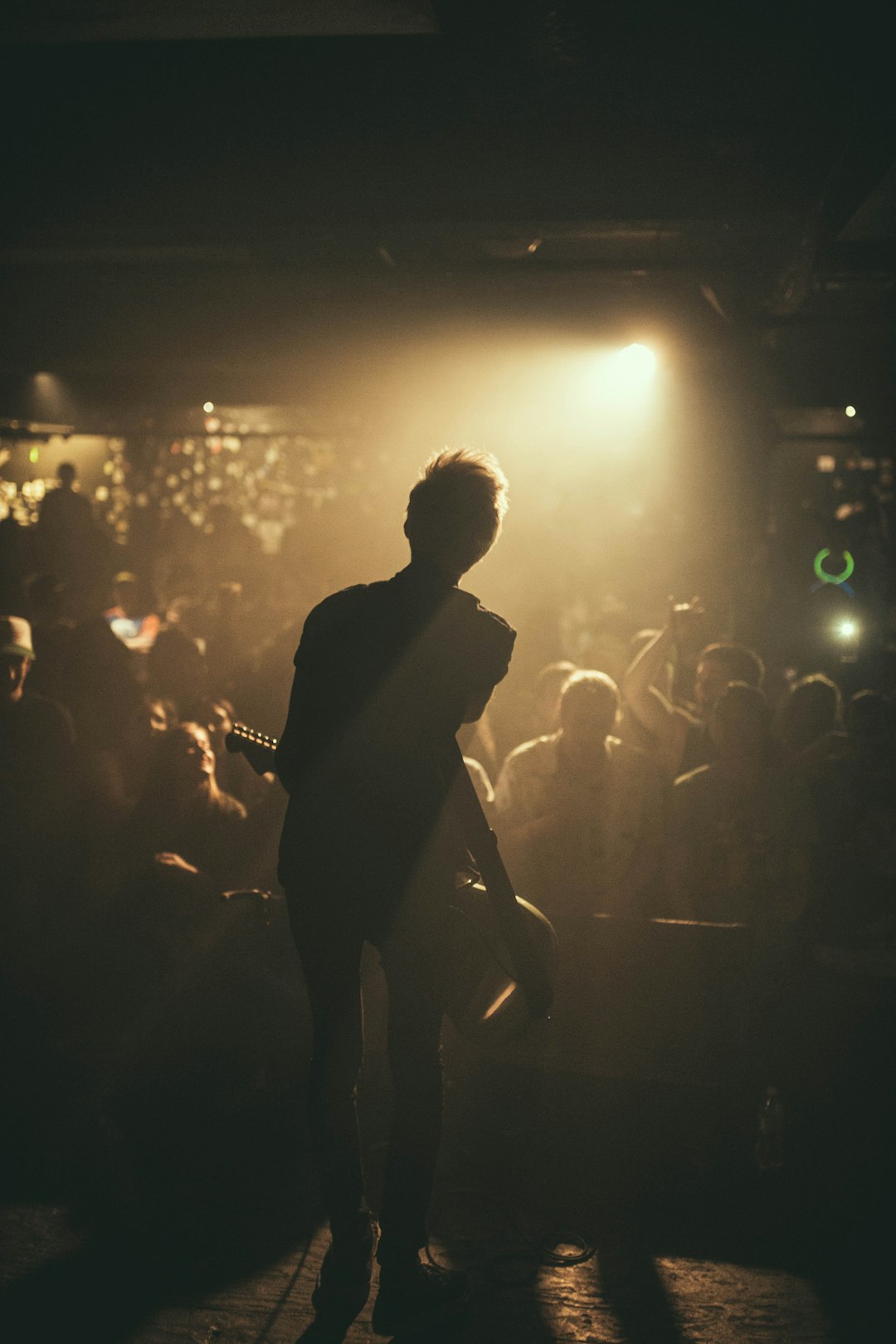 man playing guitar on stage near people