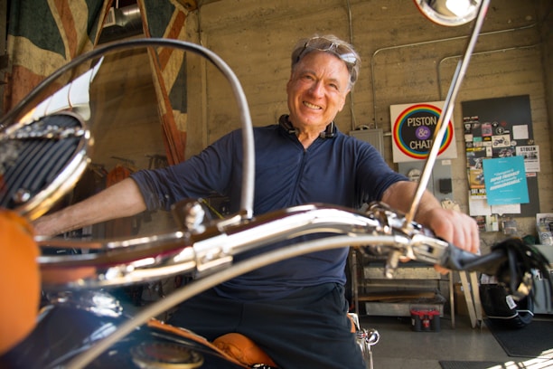 Happy customer holding a motorcycle part with a satisfied smile in a workshop setting.