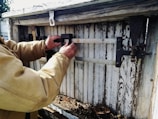 Technician adjusting springs on a classic paneled garage door during repair.