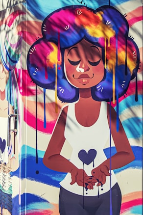 A vibrant street art mural featuring a cartoon-style character with large, colorful hair in shades of blue, purple, yellow, and pink. The character is depicted with closed eyes, expressing serenity, and holding a heart symbol. The background includes swirling, colorful patterns.