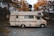 A vintage motorhome parked on a gravel path surrounded by autumn trees. The vehicle has a cream color with brown stripes and the name 'Centurion' emblazoned on its side. The setting suggests a quiet, rural area with leafy trees showcasing orange and yellow foliage.