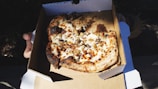 A delivery person handing over a pizza box at a customer's doorstep.