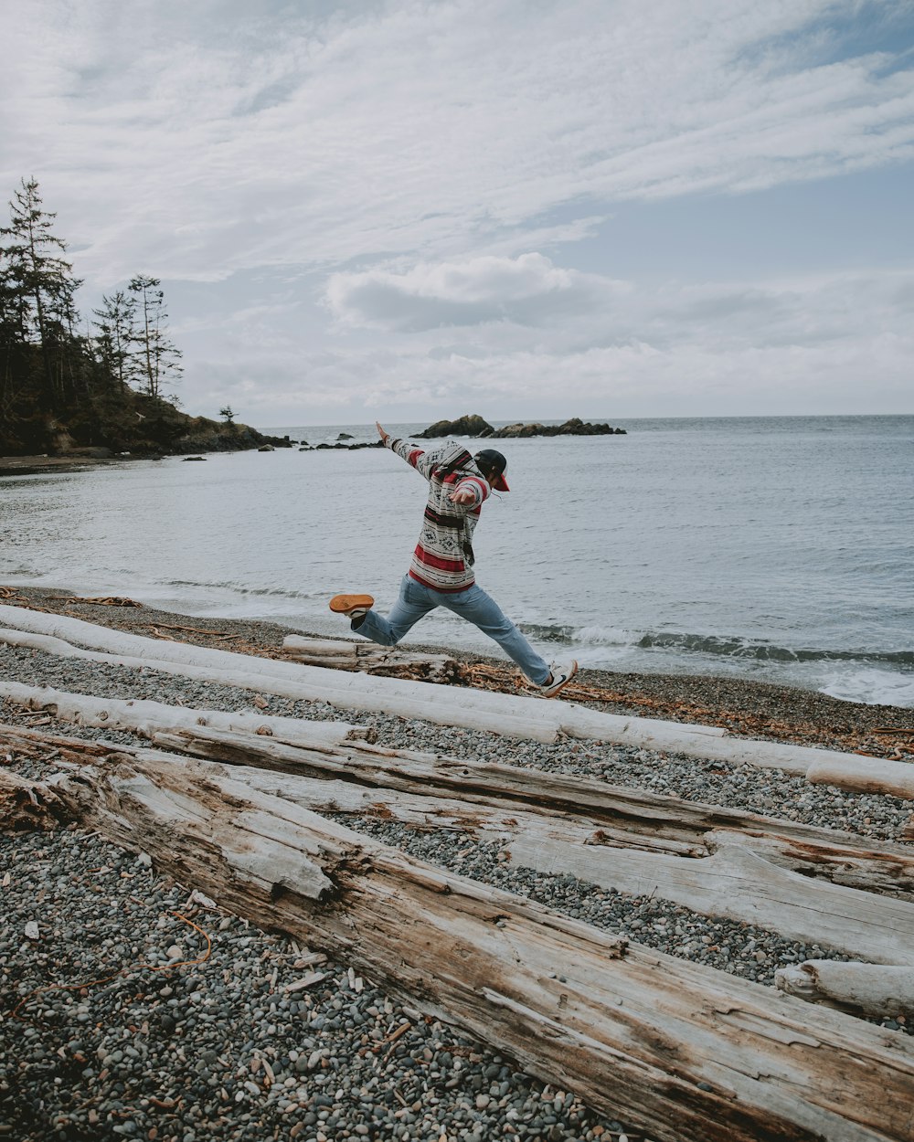 man jumping above wood logs during daytime