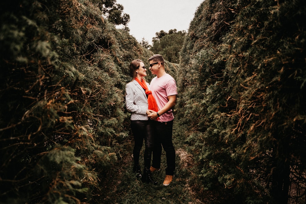 man and woman standing in middle of trees during daytime