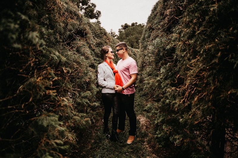 man and woman standing in middle of trees during daytime