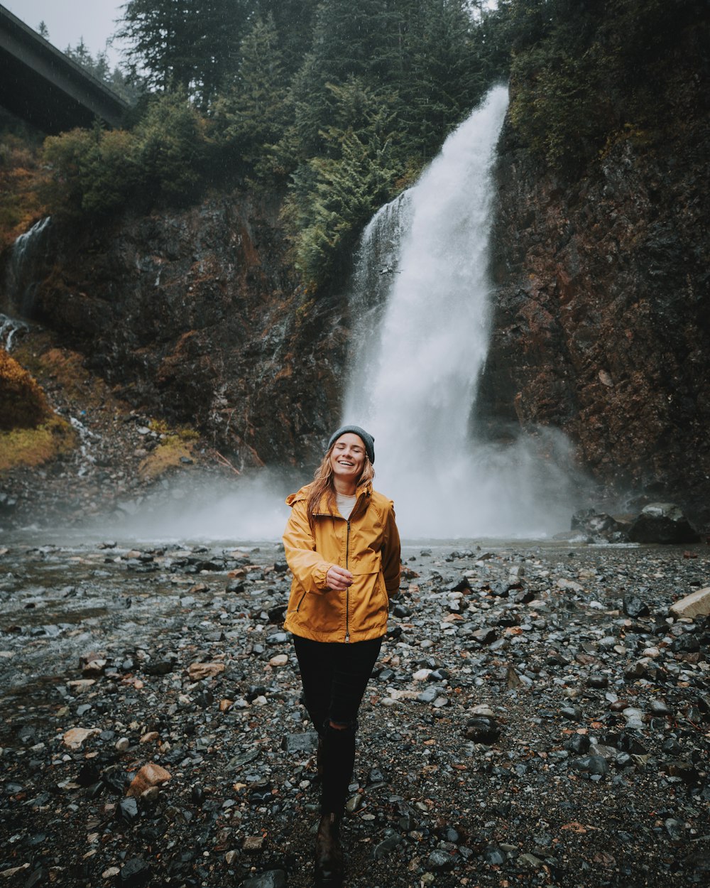smiling woman standing near waterfalls during daytime