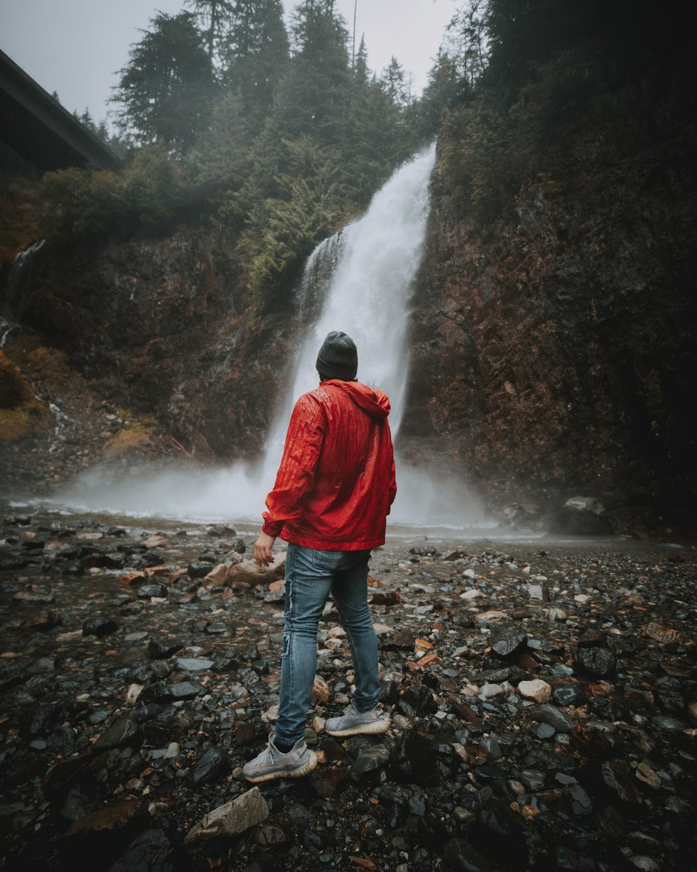 man standing near waterfalls during daytime
