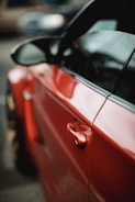 Close-up of a car door being carefully sanded in a body shop.