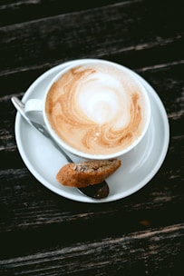 Close-up of a freshly brewed coffee with latte art on a wooden table at Biscotto.