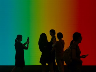 a group of people standing in front of a rainbow colored wall