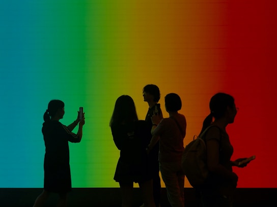 a group of people standing in front of a rainbow colored wall