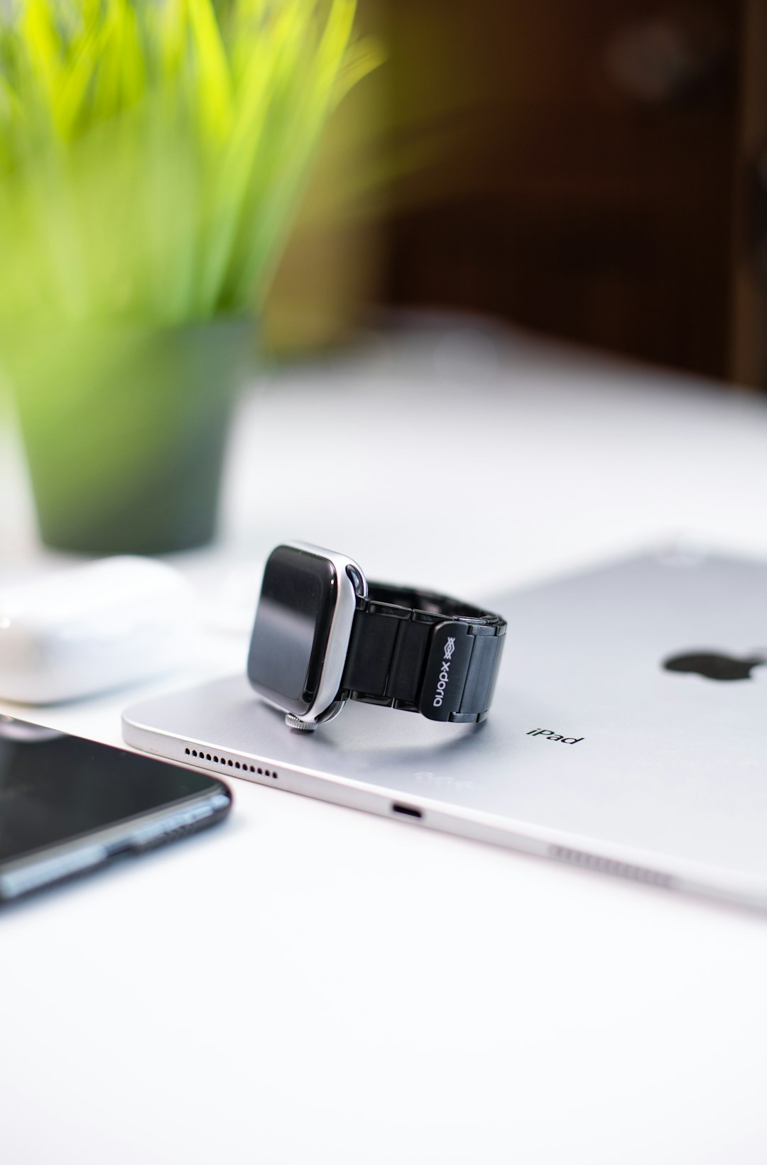 silver smartwatch with black strap on silver iPad