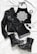 A stylish flat lay of fashion items including a black leather jacket, a black halter top with a white intricate mandala design, black denim shorts, lace-up black combat boots with studs, a pair of black sunglasses, and black bangles. The items are arranged on a white cloth background.