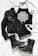 A stylish flat lay of fashion items including a black leather jacket, a black halter top with a white intricate mandala design, black denim shorts, lace-up black combat boots with studs, a pair of black sunglasses, and black bangles. The items are arranged on a white cloth background.