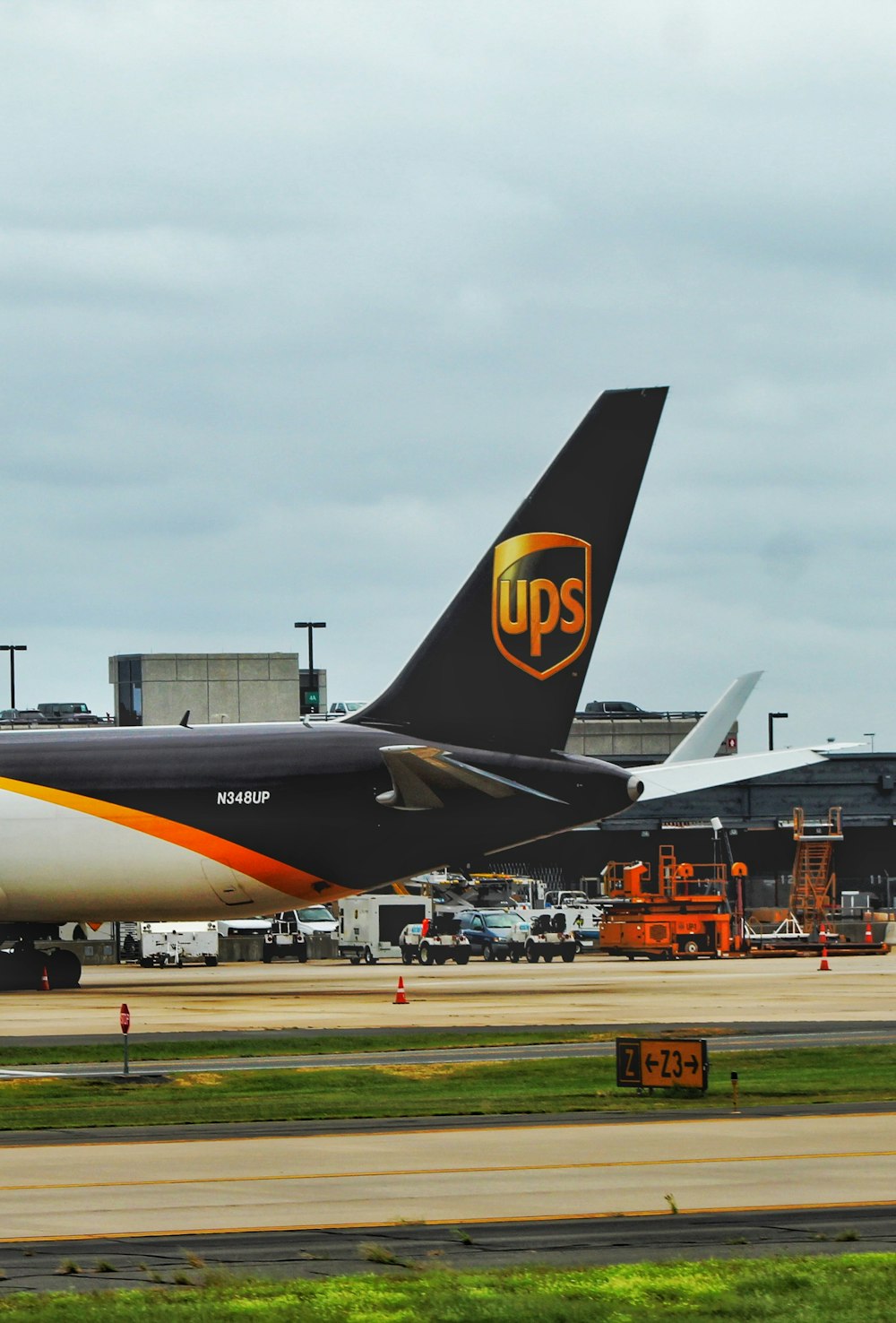 黒、白、黄色のUPS飛行機が昼間、白と青の空の下に着陸