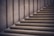 Stone steps leading upward with a minimalist design, featuring smooth, clean lines. The materials used give a sense of solidity and permanence, with a subtle play of light and shadow creating depth.