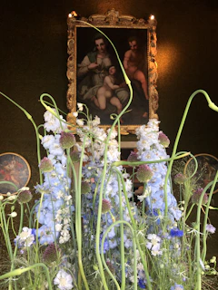 A colorful floral painting framed in ornate gold, catching warm sunlight