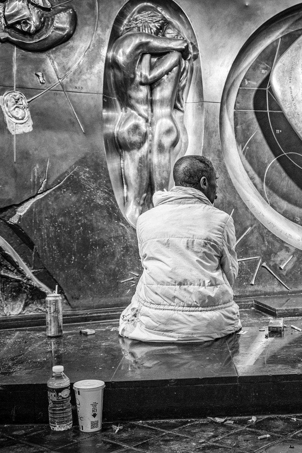 grayscale photo of man sitting on bench