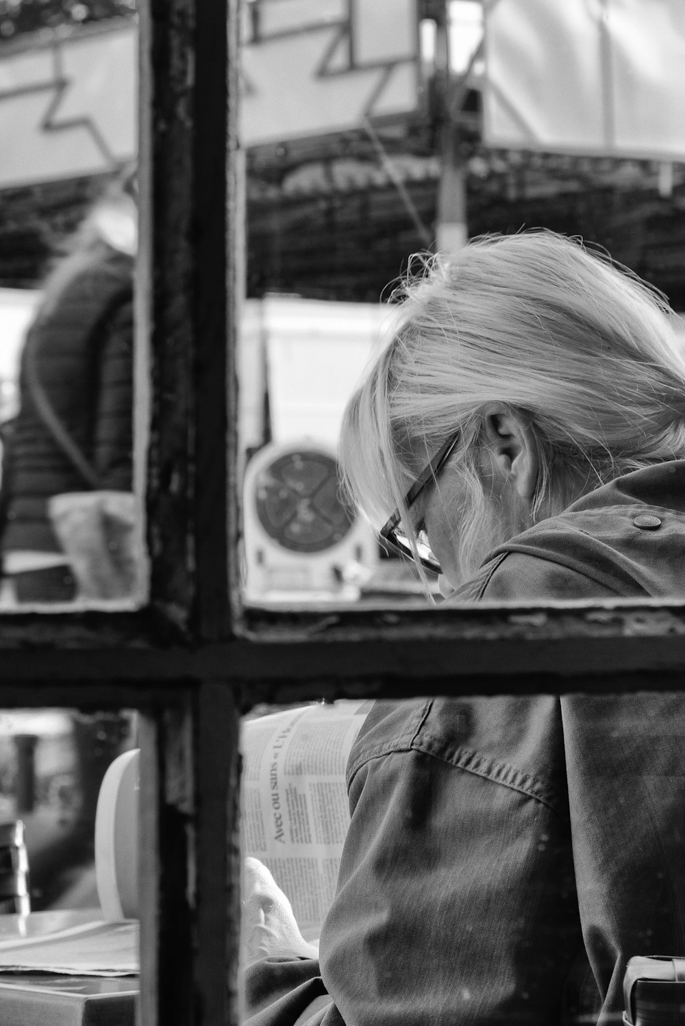 grayscale photo of woman outside window