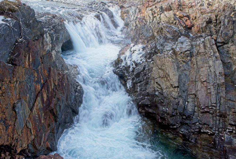 waterfalls by rocks during daytime