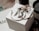 A set of jewelry items including large hoop earrings and a decorative ring are placed on top of a branded white box. The background features a dark-colored candle and some out-of-focus text, creating an elegant and sophisticated setting.