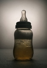 A vibrant 3D-rendered floating milk bottle glowing softly with neon green accents against a deep charcoal background.